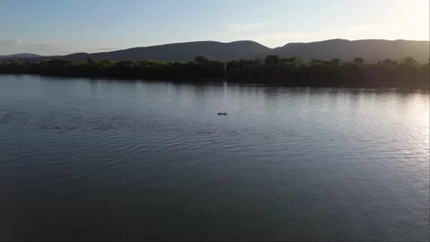 Aerial Drone Tracking Canoe on River at Sunset with Forest and Mountains Stock Footage 313830717