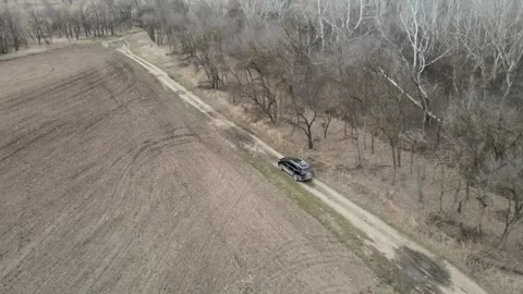 Aerial drone tracking shot of a car driving along a dirt road Stock Footage 337394631