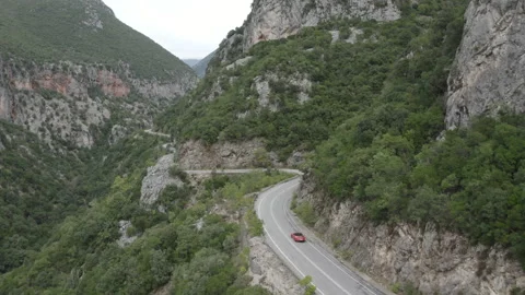 Aerial drone tracking shot of red porsche over mountain road in Greece. 動画素材 147384522