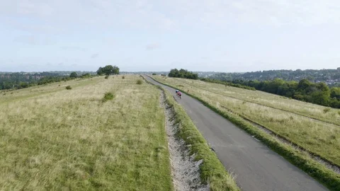 Aerial drone tracking shot of three cyclist cycling along a country road Stock Footage 128015000