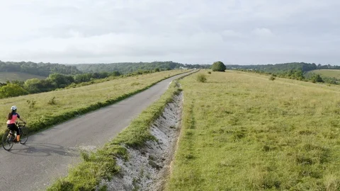 Aerial drone tracking shot of three cyclist cycling along a country road Stock Footage 128018039