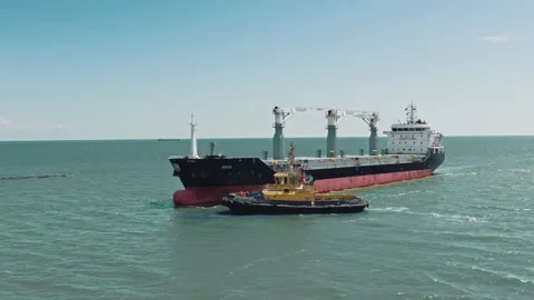 Aerial drone video of cargo container ship guided by yellow tug assistive boat Stock-Footage 132414652