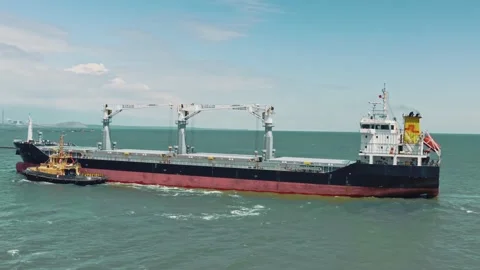 Aerial drone video of cargo container ship guided by yellow tug assistive boat Stock-Footage 132415017