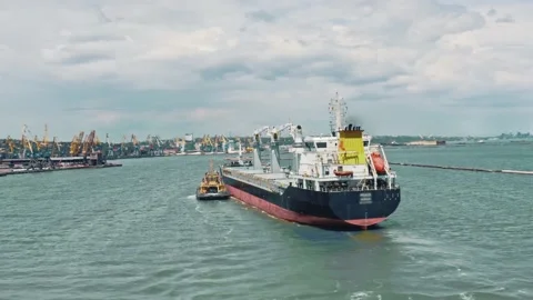 Aerial drone video of cargo container ship guided by yellow tug assistive boat Stock Footage 132415533