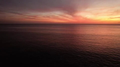 Aerial drone view above water heading towards a magenta sunset during the summer Stock Footage 252154843