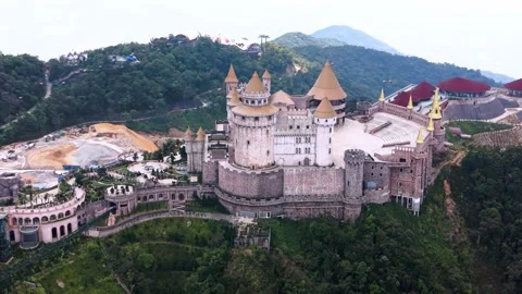 Aerial drone view of Ba Na Hills SunWorld castle complex surrounded by forested Stock Footage 339983672