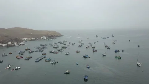 Aerial drone view of a beach with many fishing boats close to shore on a cloudy Video stock 155803832