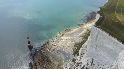 Aerial drone View of Beachy Head Lighthouse beneath towering white chalk cliffs Stock Footage 342296502