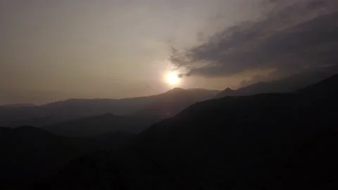 Aerial drone view between dark mountains with the background sun shining in the Vidéo 199633226