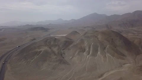 Aerial drone view of a big mountain in the desert next to the road with cars wit Vidéo 197584499