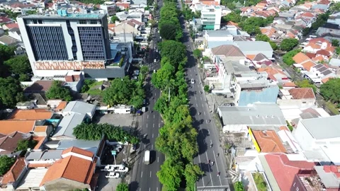 Aerial drone view of busy multi-lane city street with traffic and green trees Stock Footage 330086342