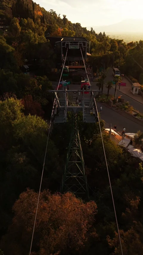 Aerial drone view of a cable car gondola moving over the green trees at Cer.. Video stock 339210489