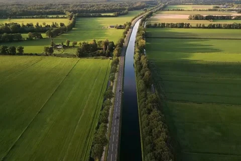 Aerial Drone View Of Canal Through Green Farmland - Top Down Agriculture Video stock 343792145