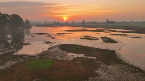 Aerial drone view capturing orange skies mirrored on glassy wetland water. Stock Footage 310937402