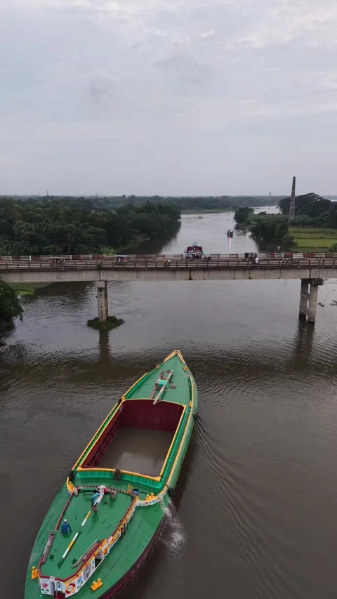 Aerial drone view of a cargo boat passing under a river bridge in village Stock Footage 341520867