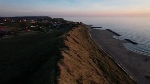 Aerial drone view of coastal cliffs and village at sunset, scenic seaside Stock Footage 343539953