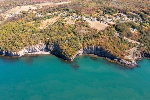 Aerial drone view of coastal cliffs homes and autumn woodland overlooking t.. Foto stock