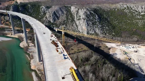 Aerial drone view of the construction of a high concrete bridge over the river Stock Footage 265226348