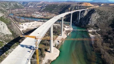 Aerial drone view of the construction of a high concrete bridge over the river Stock Footage 265226429