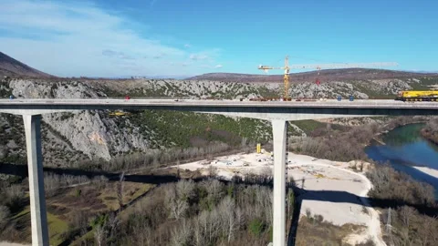 Aerial drone view of the construction of a high concrete bridge over the river Stock Footage 266828314