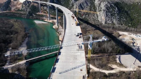 Aerial drone view of the construction of a high concrete bridge over the river Stock Footage 266828358