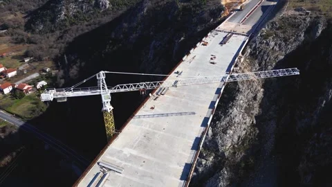 Aerial drone view of the construction of a high concrete bridge over the river Stock Footage 267695150