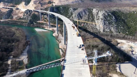 Aerial drone view of the construction of a high concrete bridge over the river Video stock 267695262