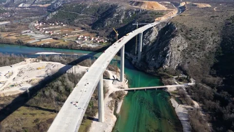 Aerial drone view of the construction of a high concrete bridge over the river Stock Footage 270208946