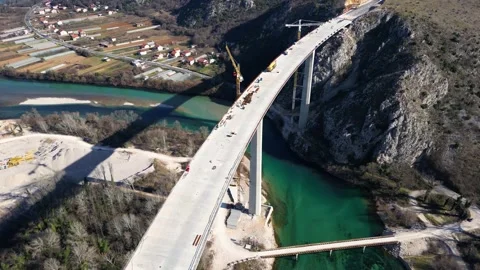 Aerial drone view of the construction of a high concrete bridge over the river Stock Footage 271360681