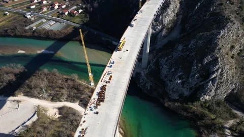 Aerial drone view of the construction of a high concrete bridge over the river Stock Footage 275029075