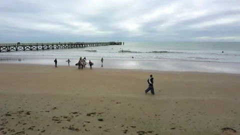 Aerial drone view of a couple doing seaside stroll near surf spots on beach Stock Footage 144552586