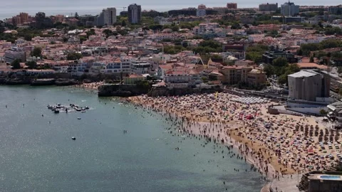Aerial drone view of crowded Conceicao Beach in Cascais, Portugal on a sunny Stock Footage 280355407