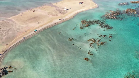 Aerial drone view of a curving sandy spit and shallow turquoise lagoon dotted Stock Footage 339301539