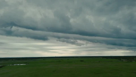 Aerial drone view of Dark storm clouds rolling over open green fields before Stock Footage 340382633