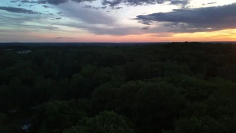 Aerial drone view of dramatic sunset over lush green forest horizon Stock Footage 336516249