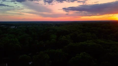Aerial drone view of dramatic sunset over lush green forest horizon Stock Footage 336516272