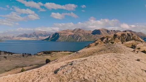 Aerial drone view of dry hillside ridge overlooking blue lake and mountains Stock Footage 345466958
