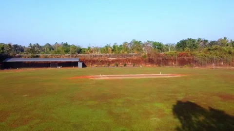 Aerial drone view of an empty cricket ground with a red clay pitch, green Stock Footage 327427521