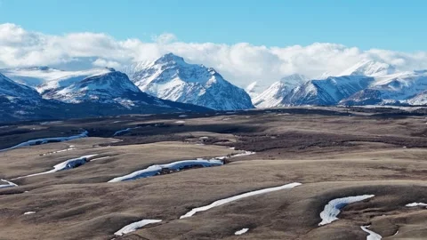 Aerial drone view of an expansive brown plain dotted with snow patches and Stock Footage 332085817