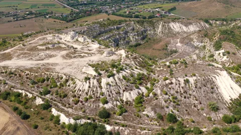 Aerial drone view of Expansive limestone quarry showing white hills and green Stock Footage 345500994