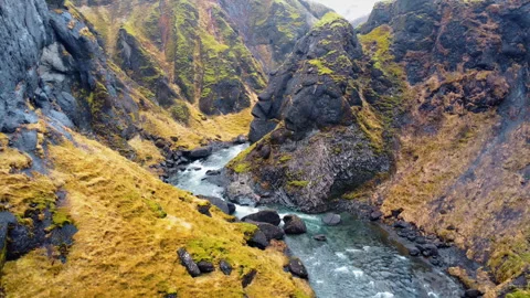 Aerial drone view of a fast flowing river running between rugged cliffs and Stock Footage 321850765