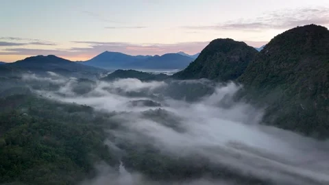 Aerial Drone View of Flowing Mist Around Karst Peak  at Pink Sunrise Stock Footage 335806481