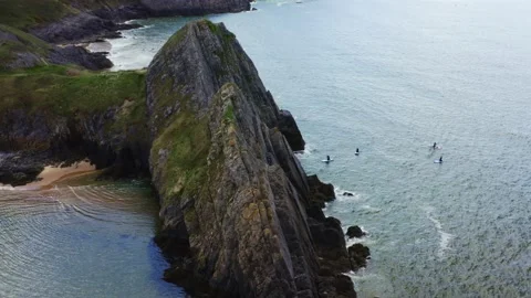 Aerial drone view flying around three cliffs at high tide. Three Cliffs Bay Stock Footage 192536289