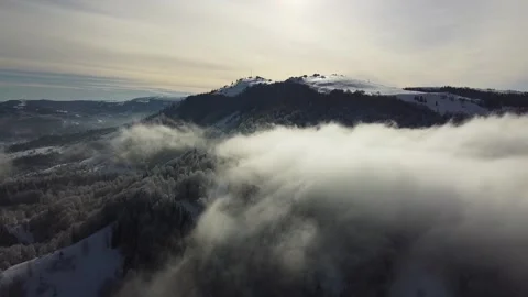 Aerial Drone View of Fog Rolling Over Snowy Mountain Forest Stock Footage 324565653
