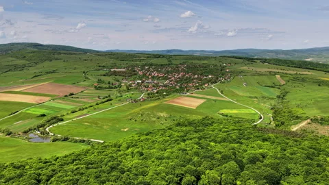 Aerial drone view of a forest canopy giving way to fields and a village, 스톡 동영상 336315159