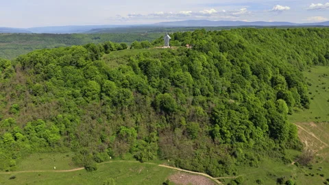 Aerial drone view of a forested hillside with a dirt road and a hilltop Stock Footage 336314965