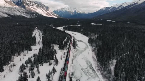 Aerial drone view of freight train through snowy Banff National Park valley 스톡 동영상 330950740