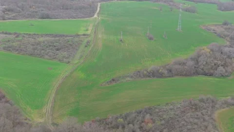 Aerial drone view of green fields, power lines and surrounding hills Stock Footage 323322240
