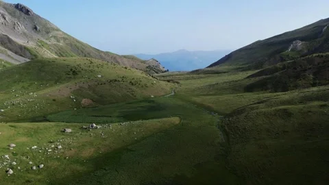 Aerial Drone View of a Green Plain Between Rocky Mountains Stock Footage 303424637