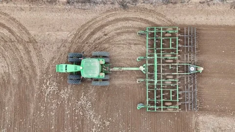 Aerial drone view of a John Deere tractor plowing a large agricultural field Stock Footage 293956941